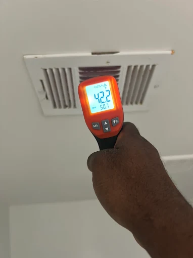 Infrared thermometer reading supply air temperature at a ceiling vent